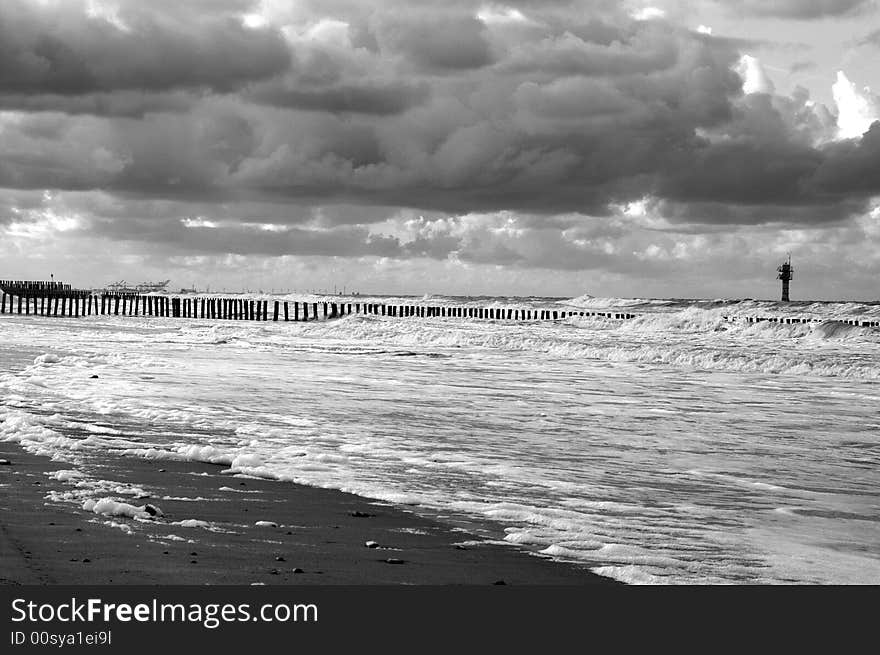 The strong wind is pushing the clouds, rolling the waves and driving the windmills in the background.