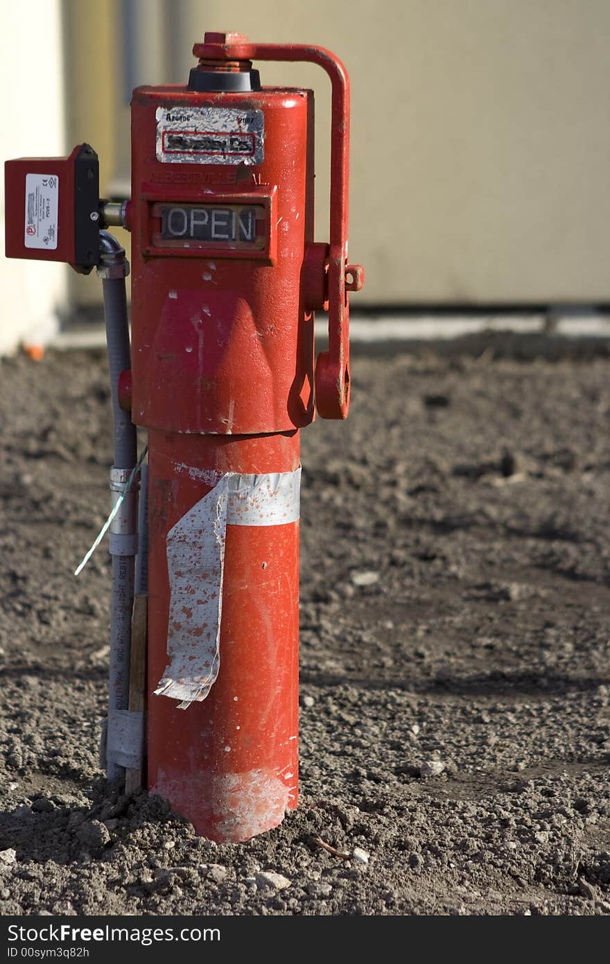 A red fire hydrant looking pipe on a construction site before any lawn was put in.