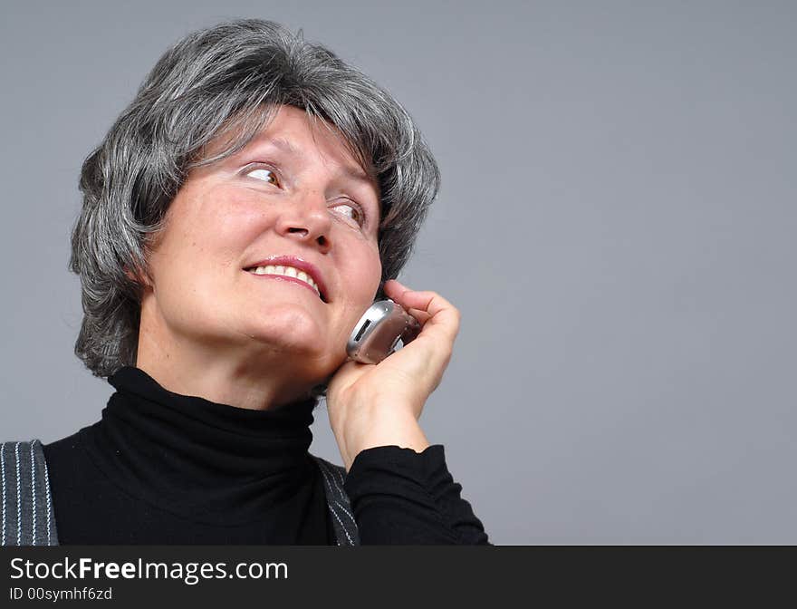 Attractive older woman chatting on the phone with copy space to the right. Attractive older woman chatting on the phone with copy space to the right