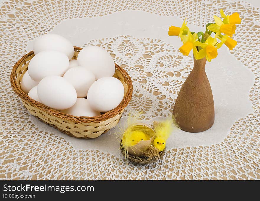 A basket of eggs, easter chicken and yellow daffodils