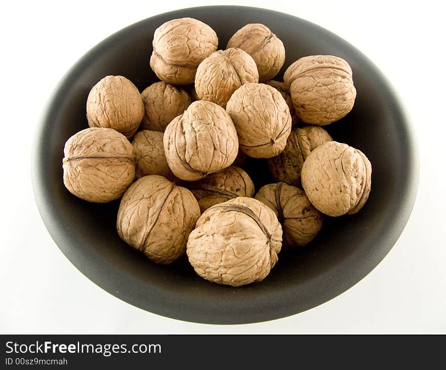 Walnuts on black plate isolated on white