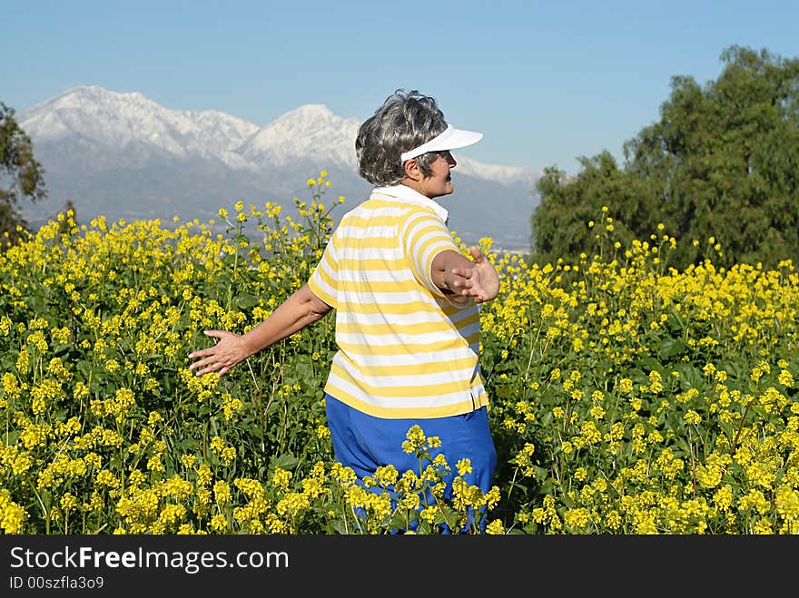 Senior woman walking through a meadow with open arms. Senior woman walking through a meadow with open arms