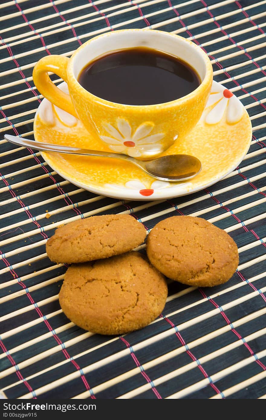 Cookies and cup with coffee on bamboo table-cloth