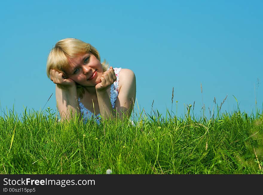 Woman lie on green grass under blue sky