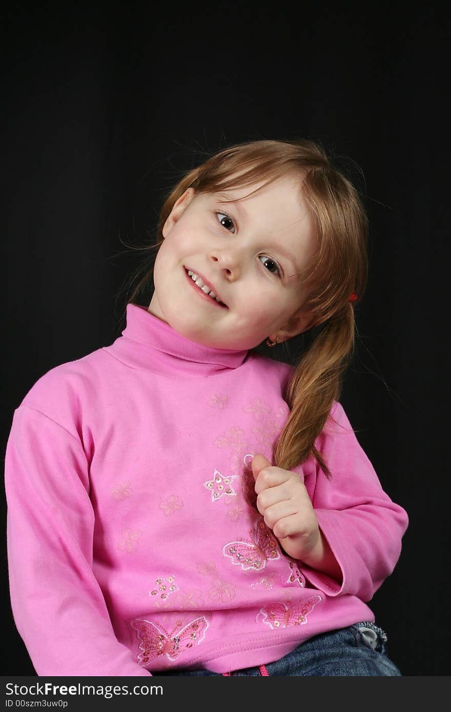 Child keeps hairs and smiles, black background