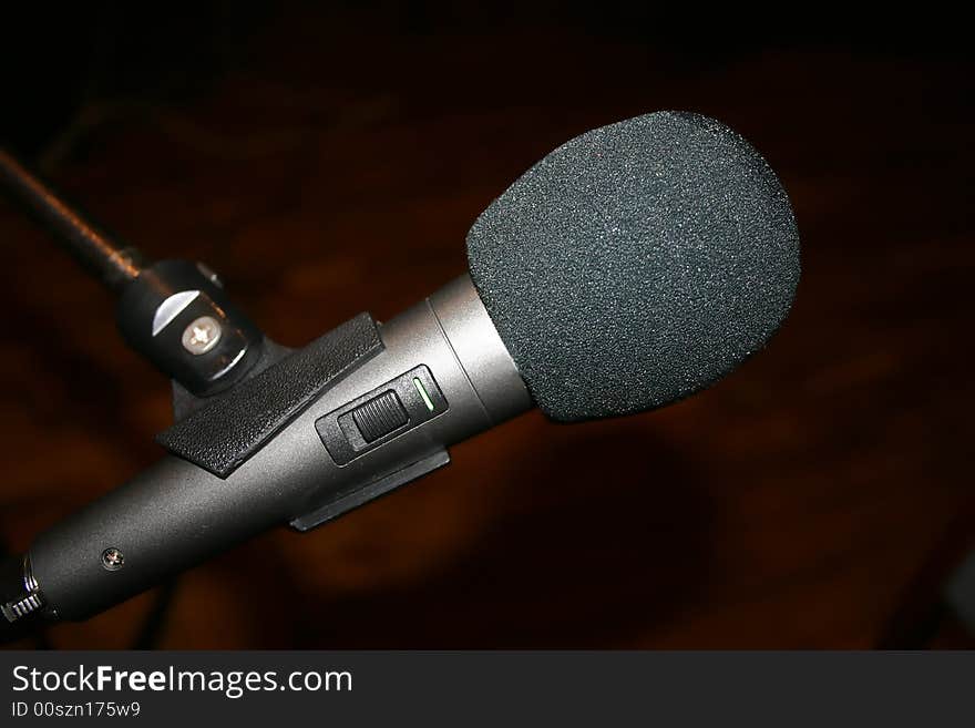 Gray microphone on stand, brown background