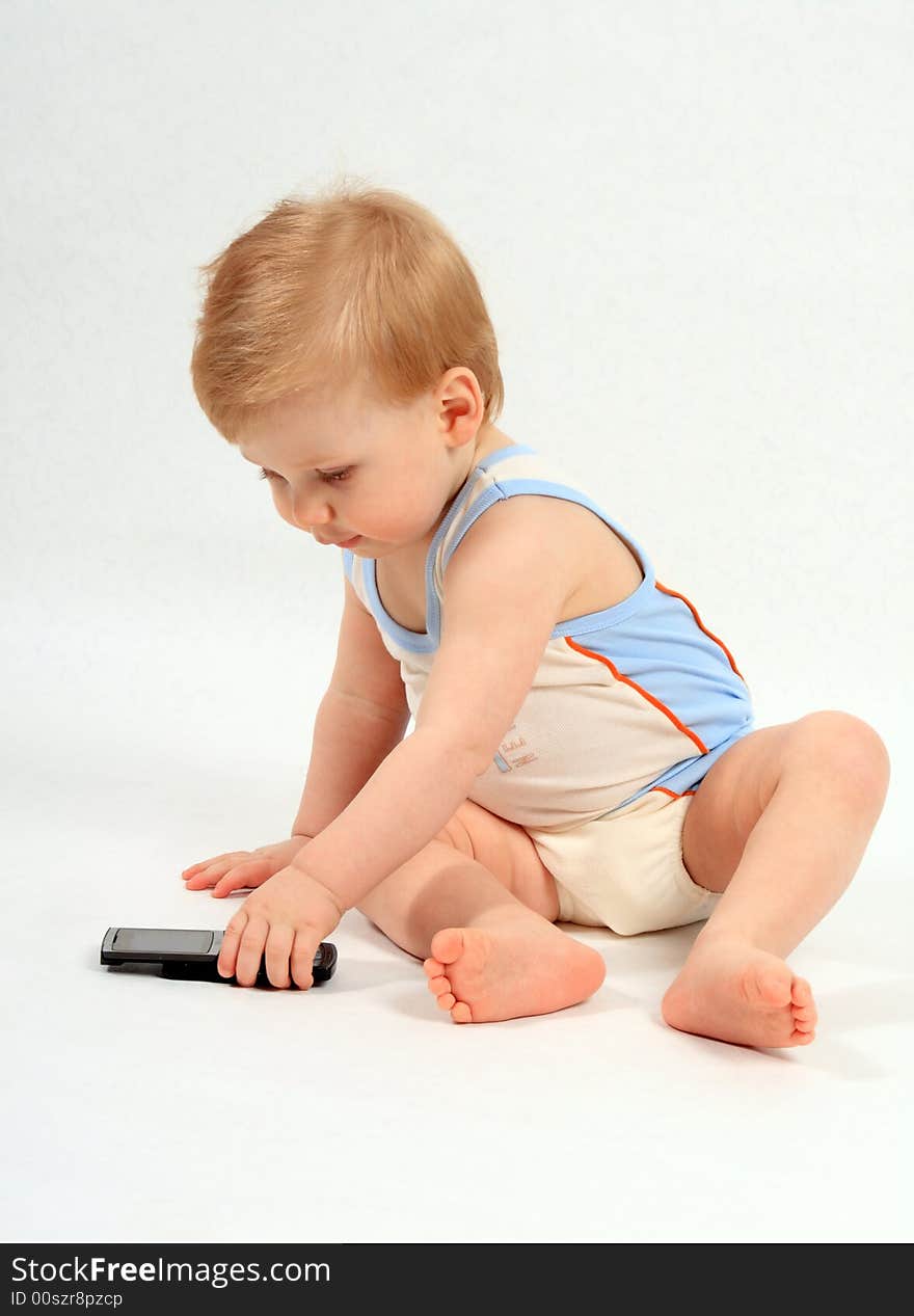 The small beautiful boy with curiosity examines a mobile phone. The small beautiful boy with curiosity examines a mobile phone