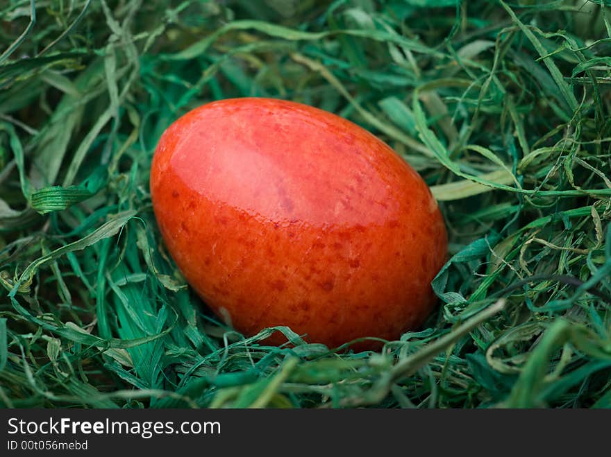 Red easter egg on the green hay. Selective focus, shallow depth of field. Red easter egg on the green hay. Selective focus, shallow depth of field.