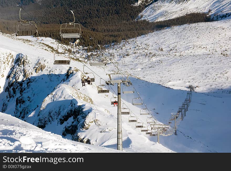 Going up by ski lift with four seat chairs