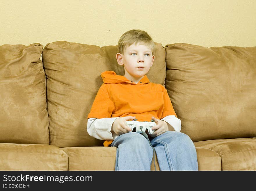 Young boy sitting on couch playing a game. Young boy sitting on couch playing a game