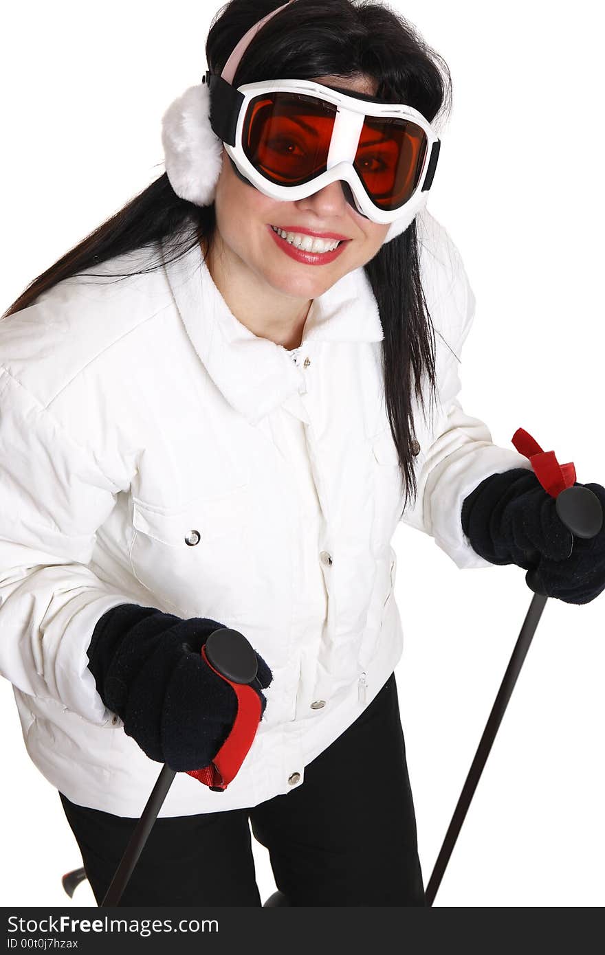 Female skier in white parka, black ski pants wearing ear muffs and ski goggles