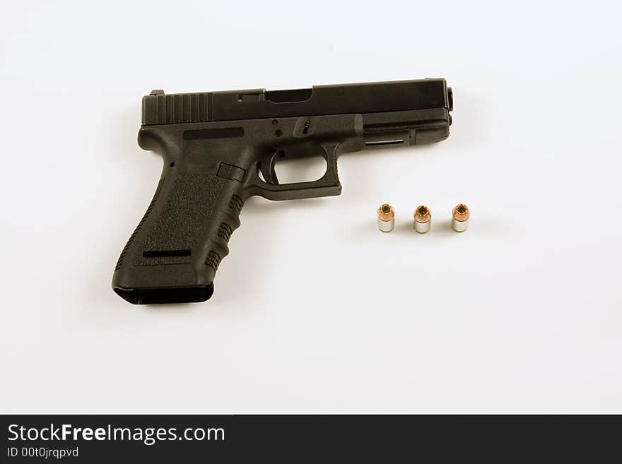 Picture of a 40mm handgun isolated on white with several hollowpoint bullets next to it.