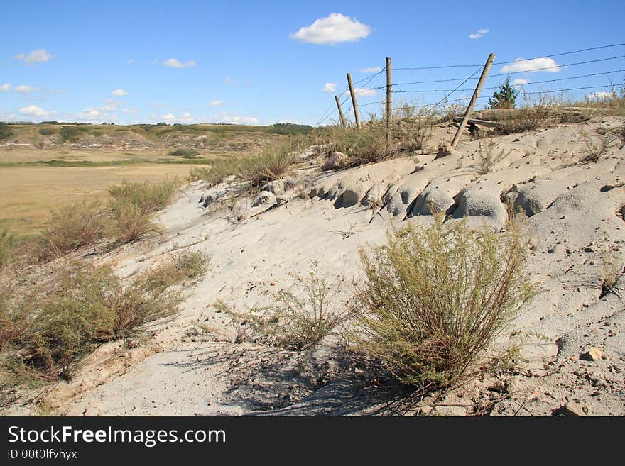 An old barbed wire fence slowly sinking into the Alberta Badlands