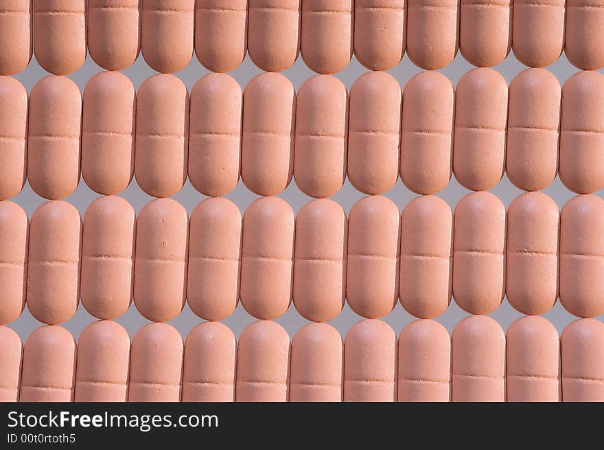 Rows of pink pills over grey. Macro. Close-up