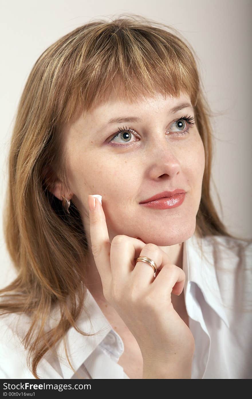 A girl putting a drop of cream on her cheek. A girl putting a drop of cream on her cheek