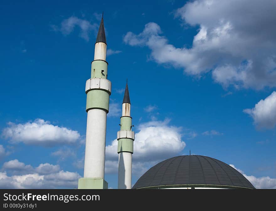 Mosque with the two minarets and dome under the blue and cloudy sky