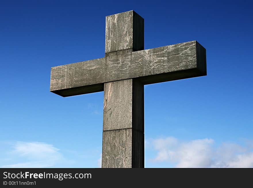 A old stone cross under a blue sky.