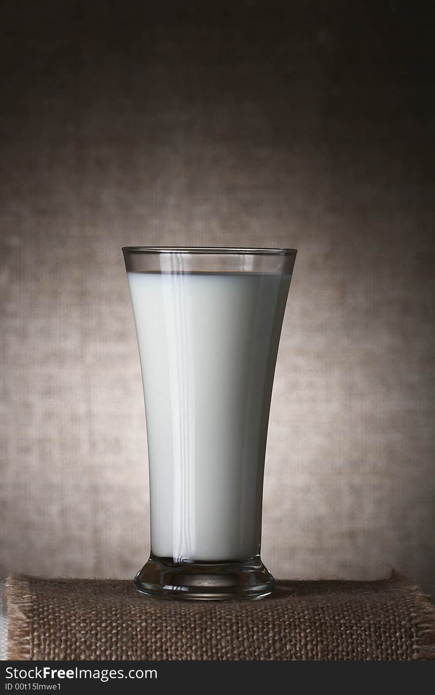 Single Glass of Milk on burlap canvas and brown rustic background, Low Key  Lighting Technique