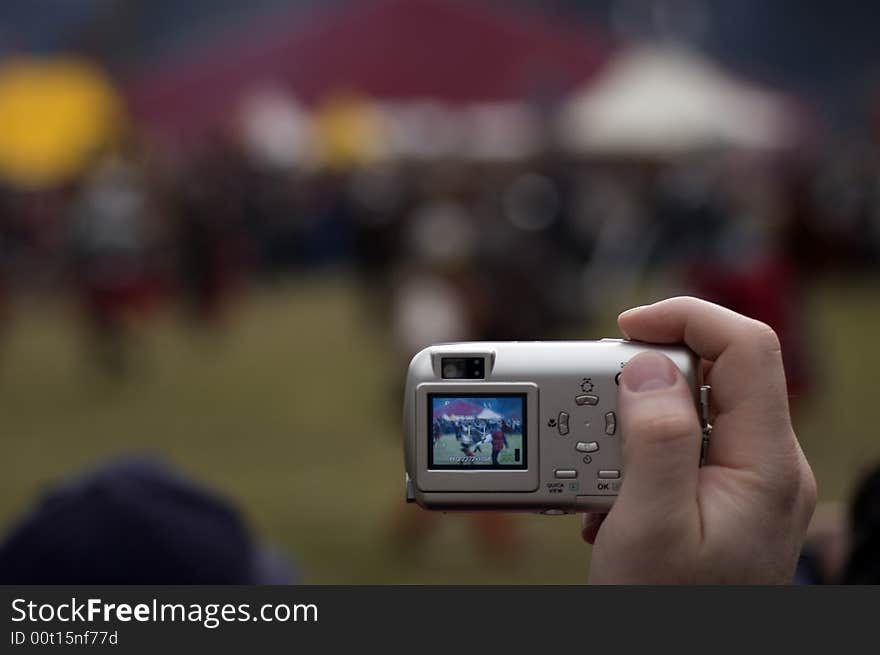 Man's hand with small digital point&shot camera on the open air event. Man's hand with small digital point&shot camera on the open air event