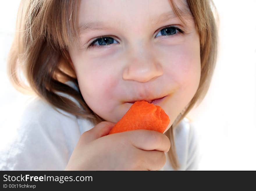 Happy little girl eating fresh carrot in the sunlight. Happy little girl eating fresh carrot in the sunlight