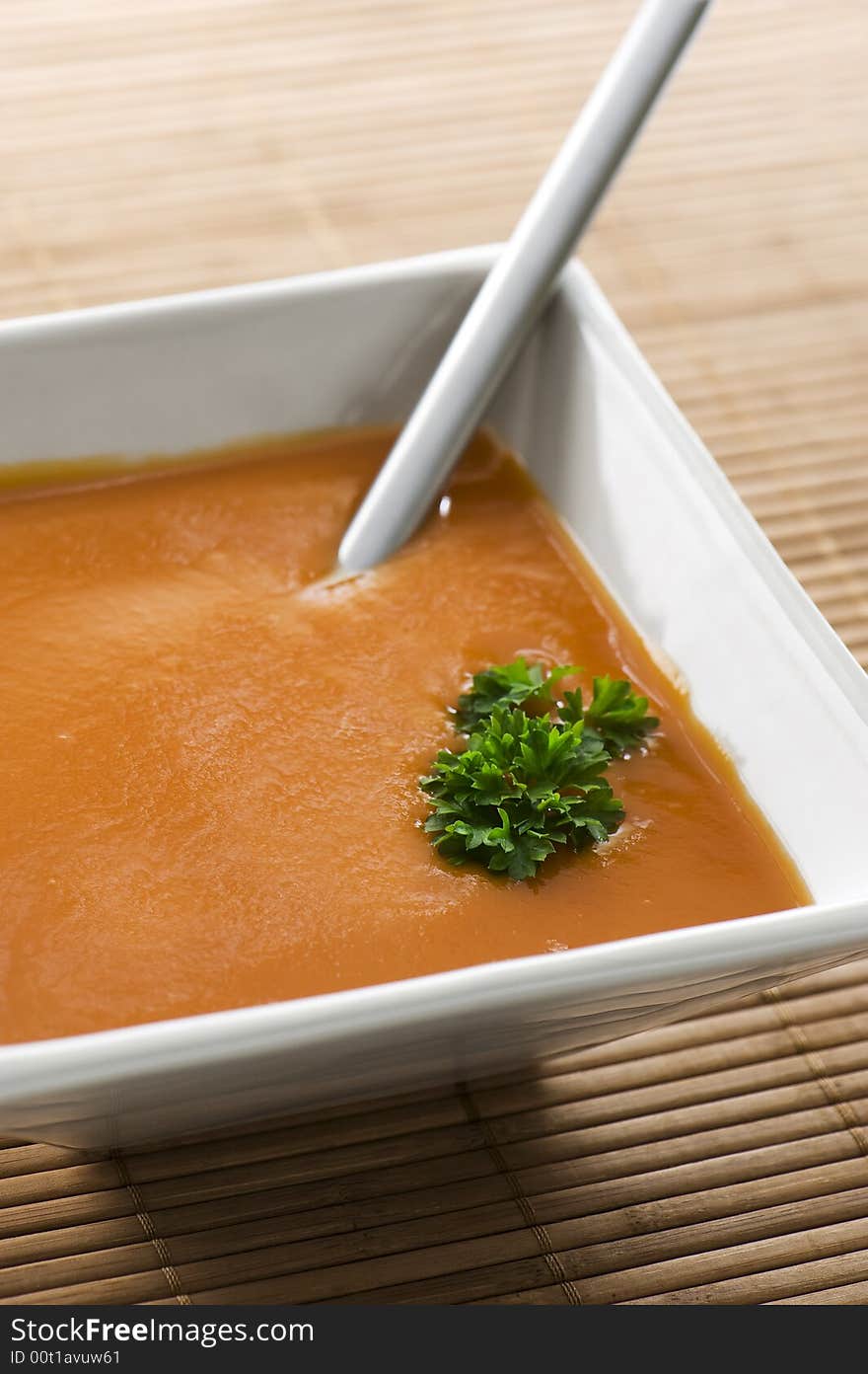 Tomato soup with chervil in square white bowl. Spoon in bowl. healthy food. Tomato soup with chervil in square white bowl. Spoon in bowl. healthy food.