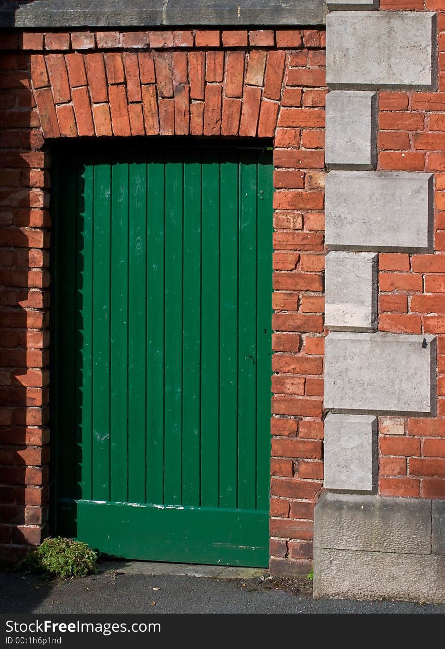 A green door in an old red brick wall