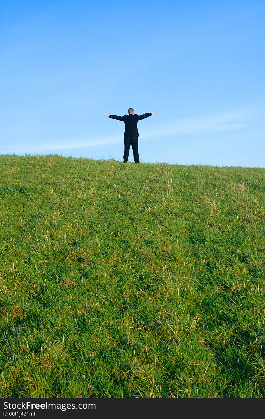 The businessman on a hill extended upwards hands