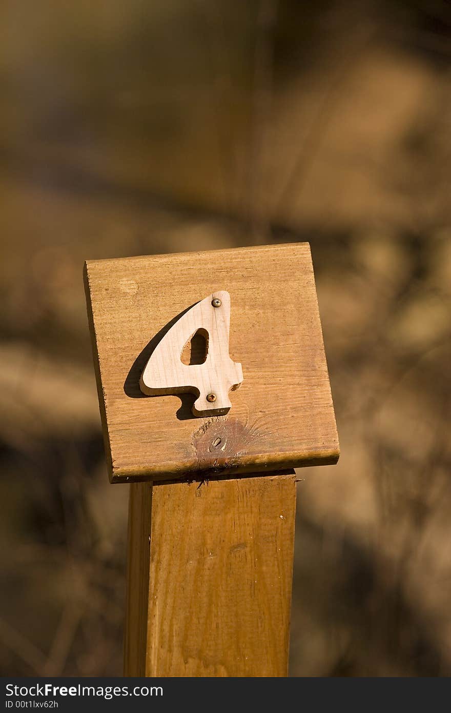 A mile marker on a woodland trail showing number four. A mile marker on a woodland trail showing number four