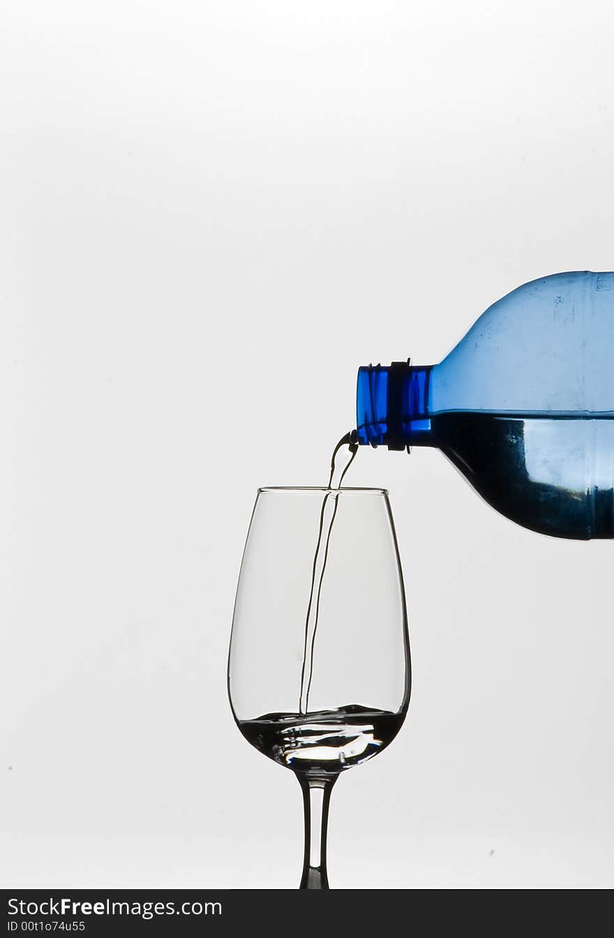 Pouring water into a wine glass from a blue bottle