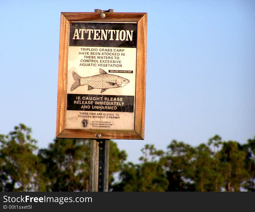 Grass Carp sign stating they are stocked and protected in this pond to control excessive aquatic vegetation