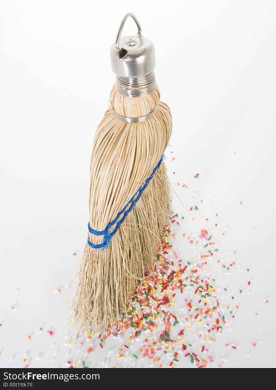 Small hand broom from above with litter of sprinkles on the ground. Small hand broom from above with litter of sprinkles on the ground.