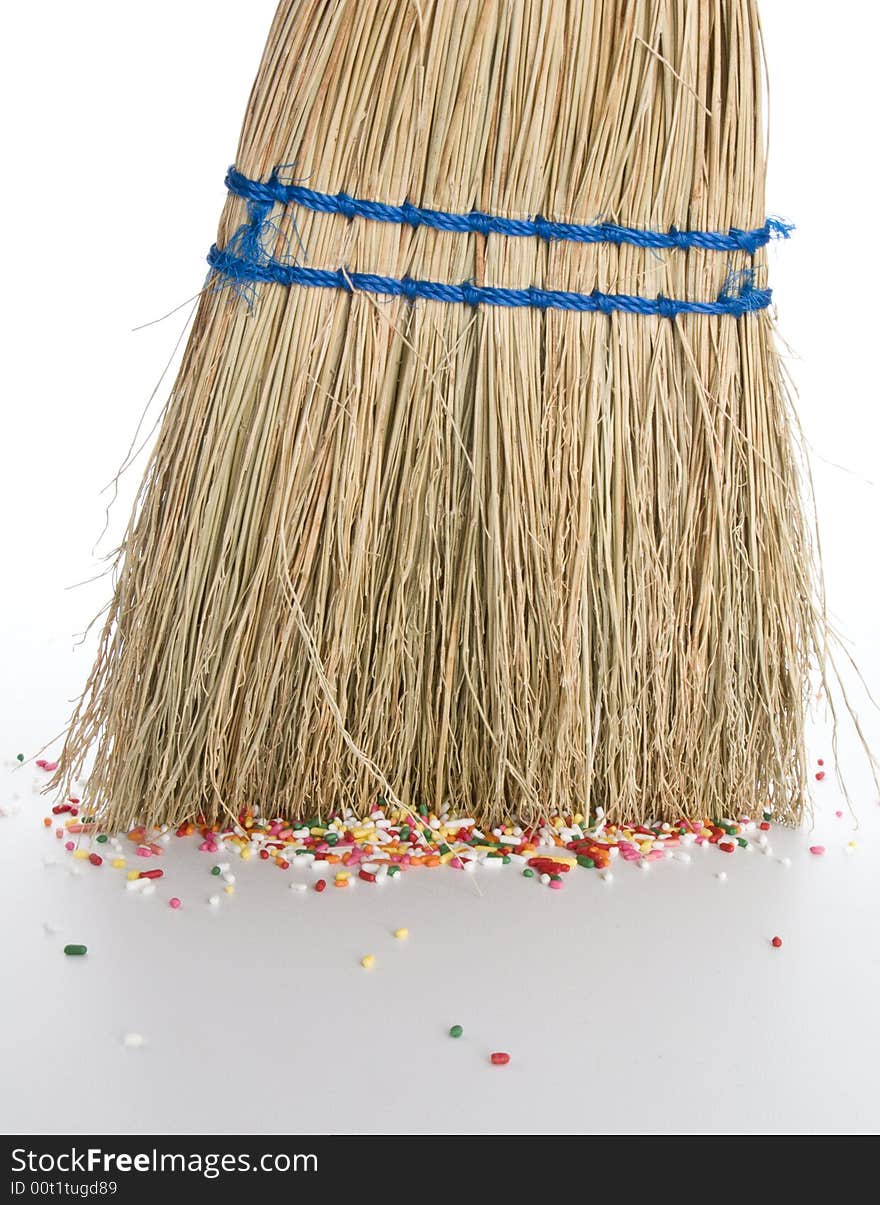 Small straw hand broom sweeping up sprinkles off floor. Small straw hand broom sweeping up sprinkles off floor.