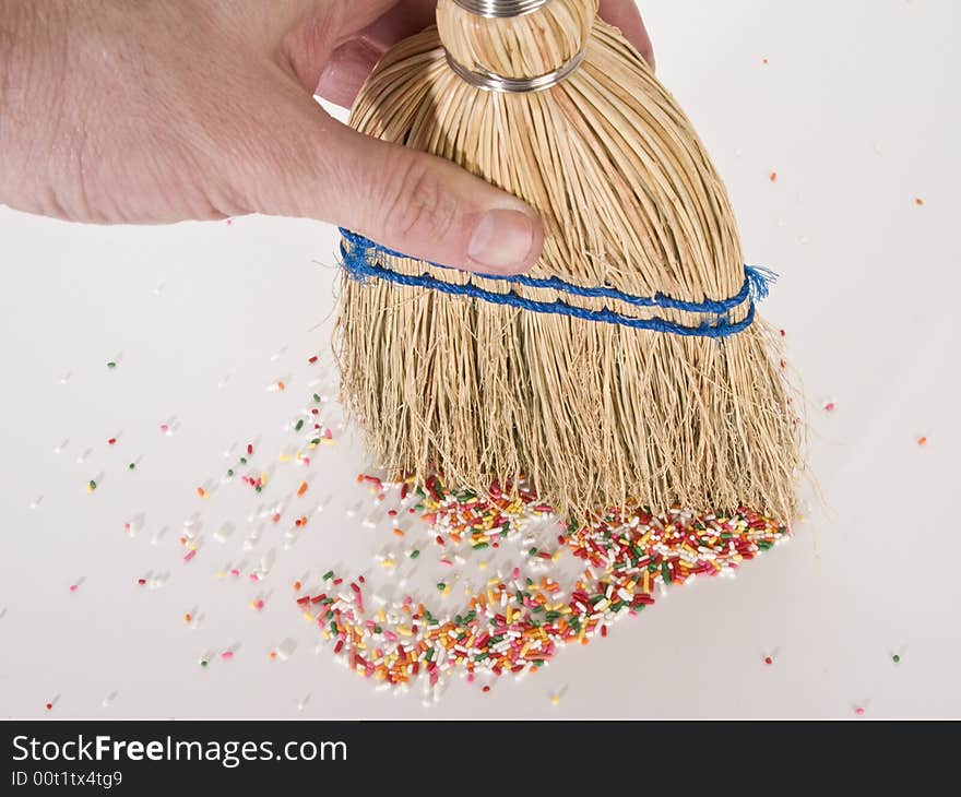 Hand sweeping sprinkles with a straw hand broom.  Photographed from a hign angle.