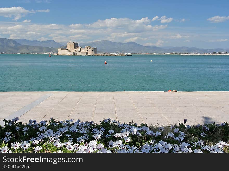 The castle island of Bourtzi, in Nafplio (Greece), with daisies in the foreground. The castle island of Bourtzi, in Nafplio (Greece), with daisies in the foreground