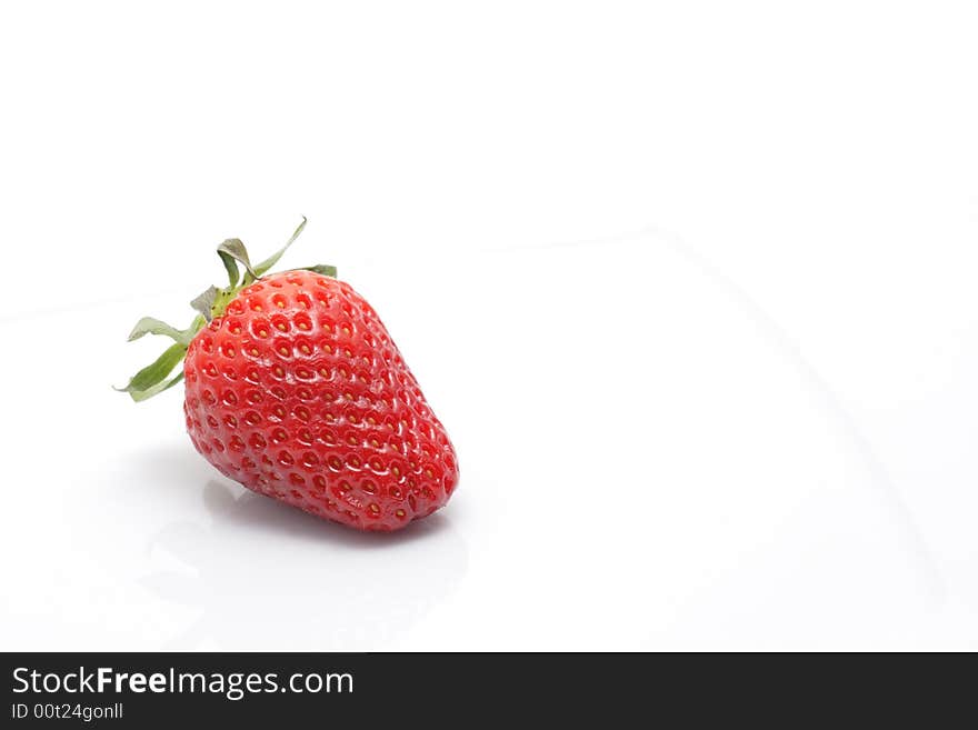 Ripe strawberry with reflection on a plate