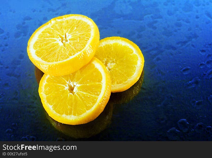 Slices of an orange on blue background with water drops