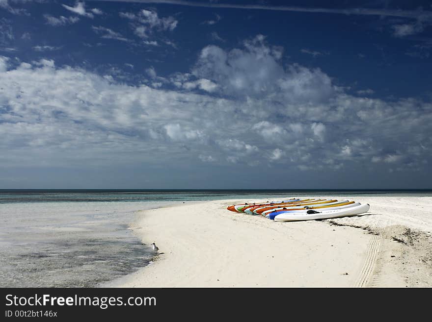 Kayaks lined up on shore of white sand beach. Kayaks lined up on shore of white sand beach