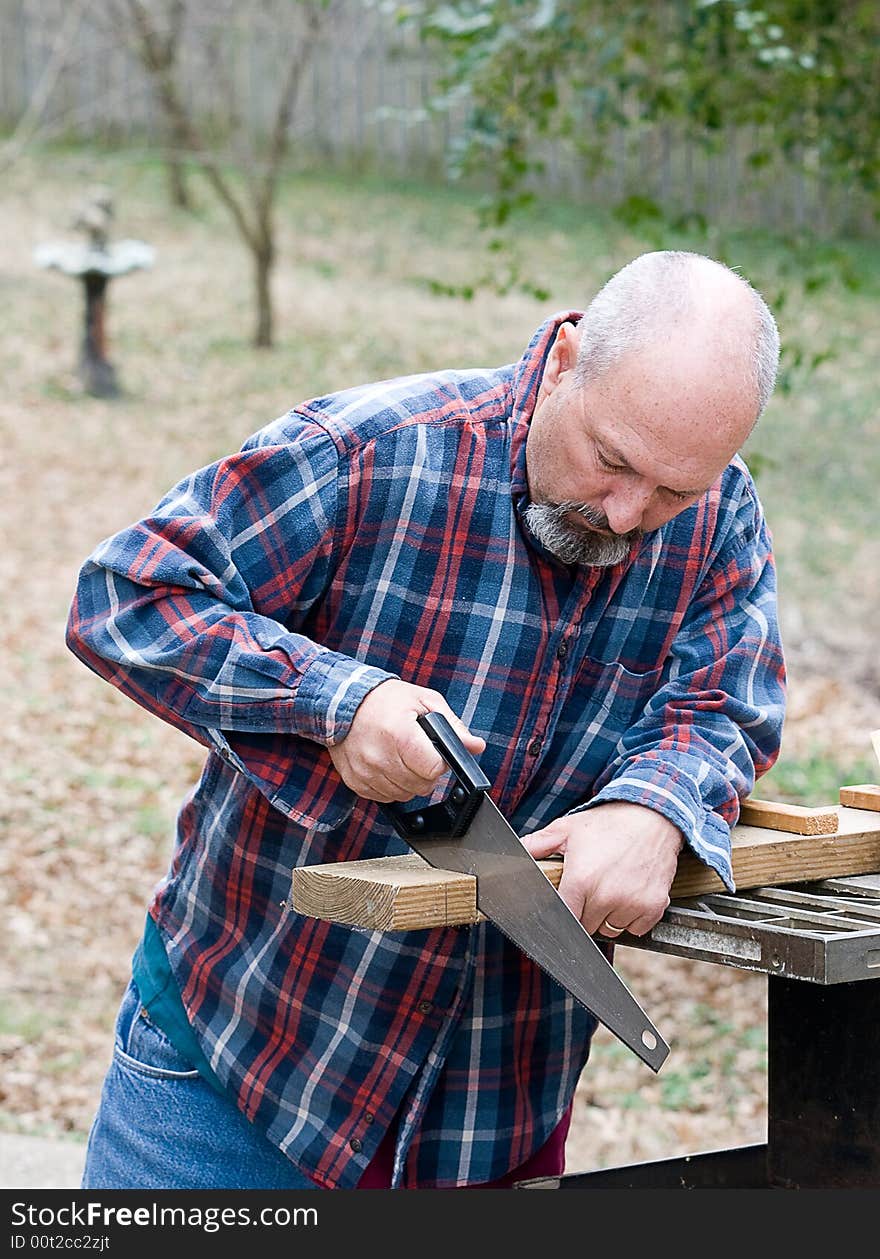 Man using hand saw to cut board. Man using hand saw to cut board