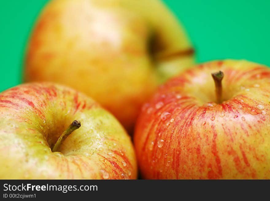 Three apples with drops on a green background