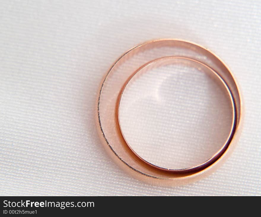 Closeup of wedding rings on a textured white background.