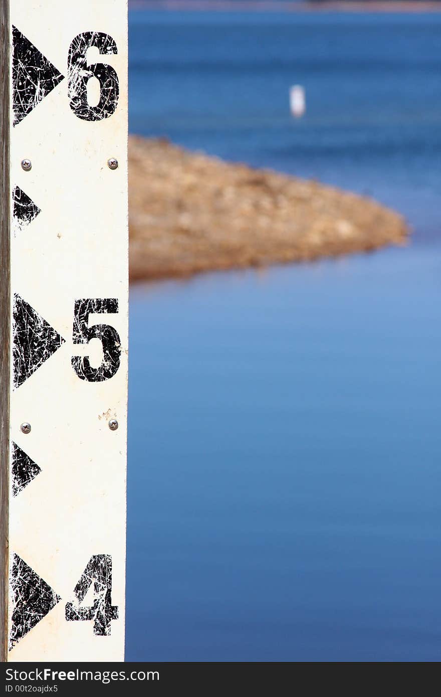 Leveling rod on lake shore showing an island. Leveling rod on lake shore showing an island