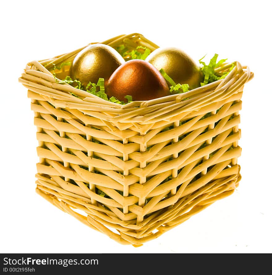 Three eggs, two gold and one bronze in a small basket on a white background. Three eggs, two gold and one bronze in a small basket on a white background