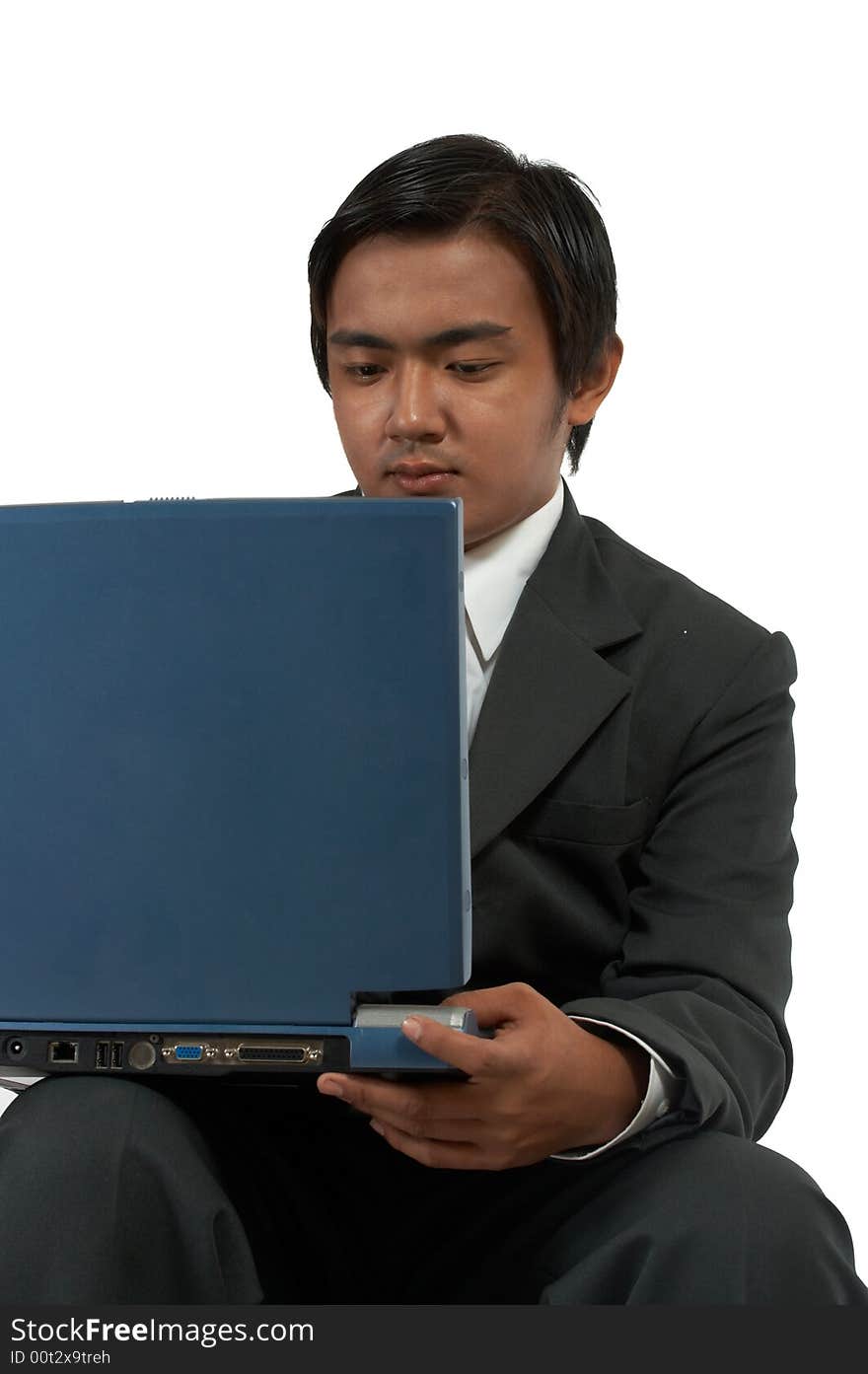 A man sitting while working on his laptop computer