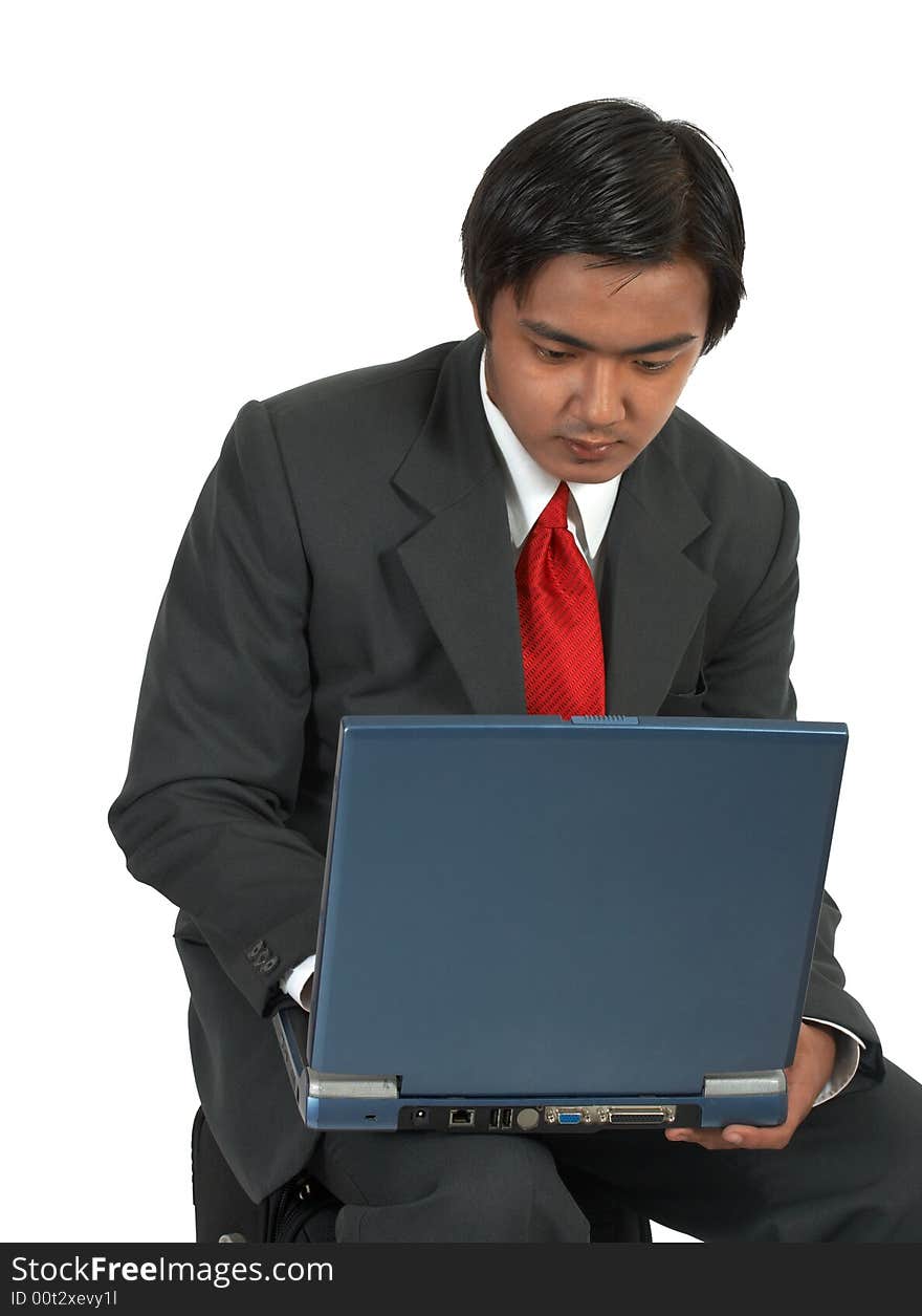 A man sitting while working on his laptop computer