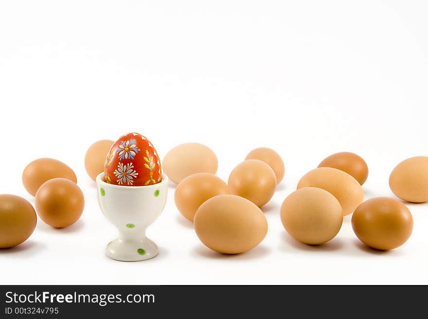 The hand painted red egg in egg-cup among natural eggs. The hand painted red egg in egg-cup among natural eggs