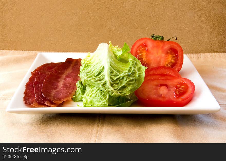 Bacon Lettuce Tomato on a white plate
3 Strips of bacon with crisp lettuce and sliced tomato.