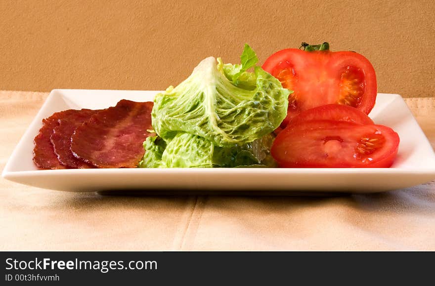 Bacon Lettuce Tomato on a white plate
3 Strips of bacon with crisp lettuce and sliced tomato.