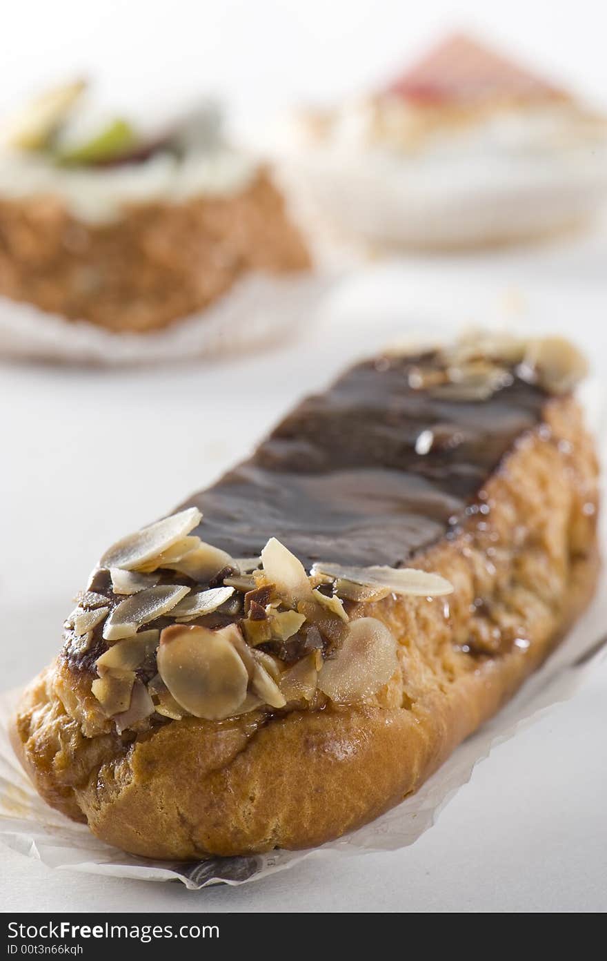 Chocolate eclair. Cupcakes in background.