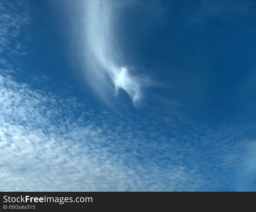 Clouds with the sign of changing weather. In the center of image is a cirrus uncinus and in the bottom are cirrus fibratus. Clouds with the sign of changing weather. In the center of image is a cirrus uncinus and in the bottom are cirrus fibratus.