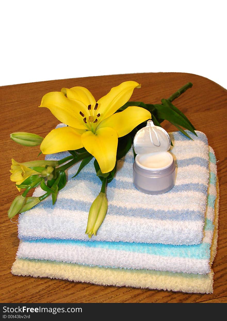 Towels, yellow flower, and cream, as a concept of beauty, massage and alternative medicine.